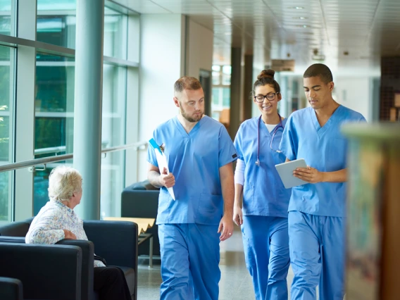 Three medical students walking in hospital hallway.