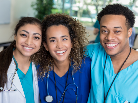 Three medical students in scrubs and white coat.