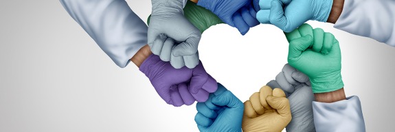 Hands in different colored gloves making heart shape.
