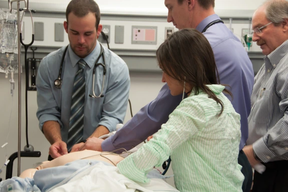 Doctors training in simulation lab to perform medical procedures.