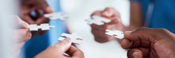 Medical professionals holding puzzle pieces.